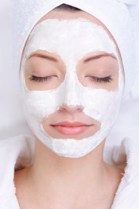 young female face with cosmetic mask - beauty salon